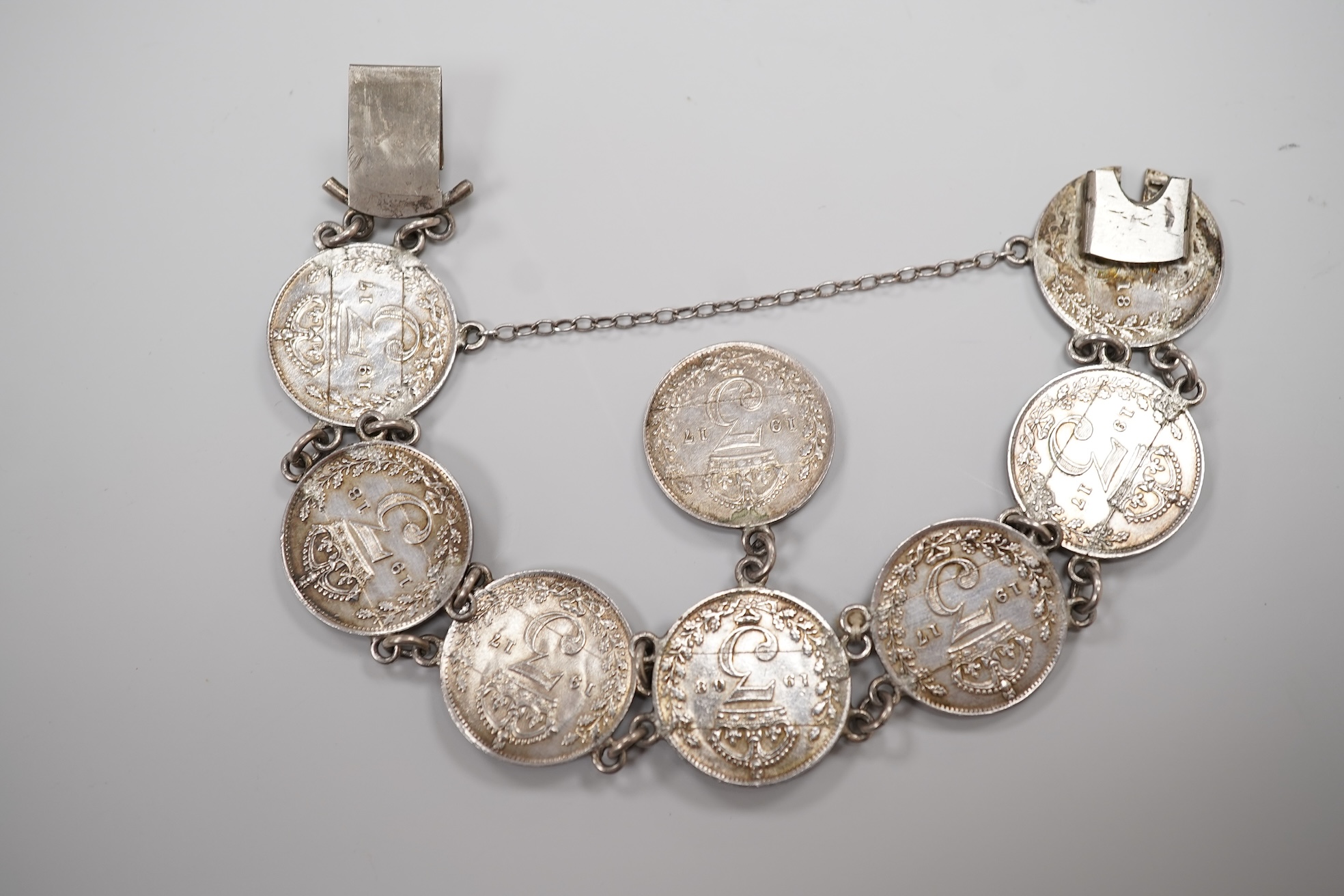 A cased early 20th century 9ct and single stone split pearl set bar brooch, 42mm and a white metal coin bracelet.
